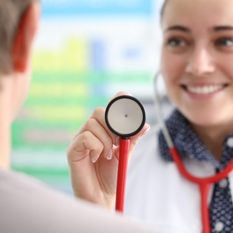 Female doctor shows patient stethoscope membrane. Bad habits and seasonal diseases. Patient is referred to hospital. Therapist's appointment provides comprehensive definition well-being